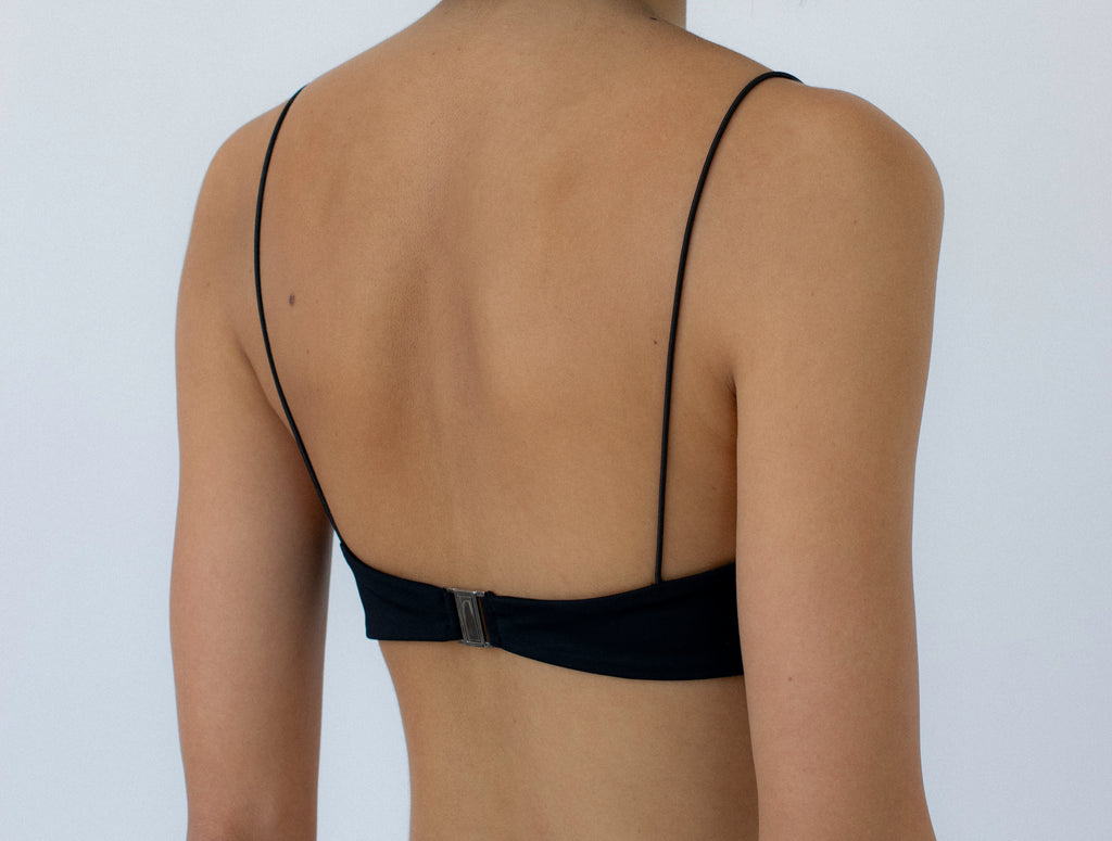 person wearing a black bralette bikini top against a white background