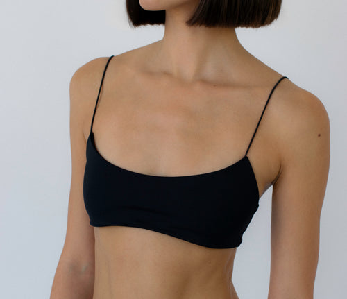 person wearing a black bralette bikini top against a white background