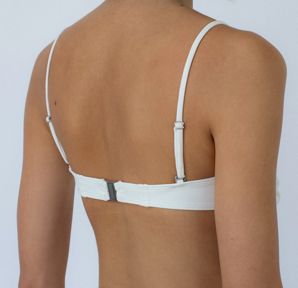 ivory balconette bikini top with metal clasp on a model against a white background