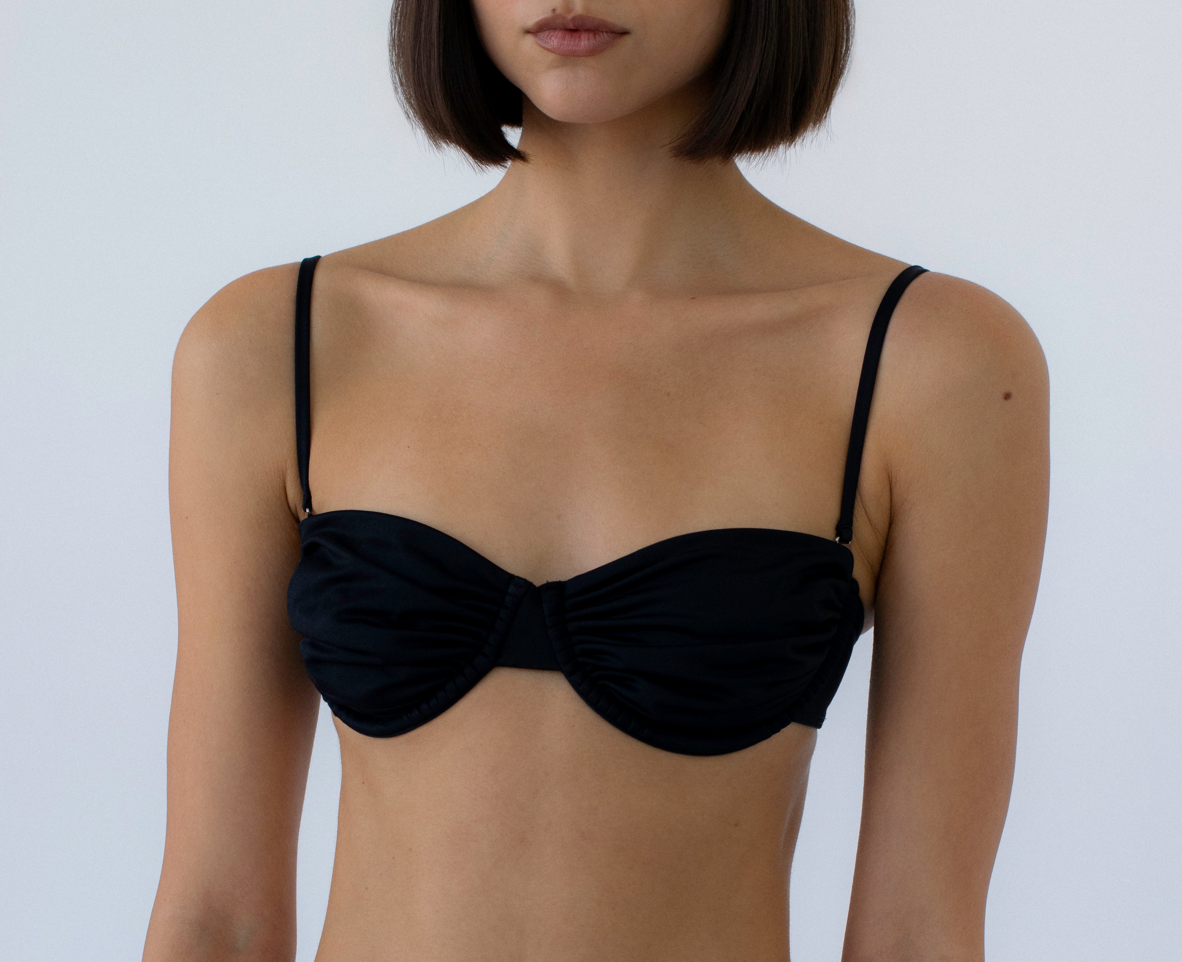 black ruched balconette bikini top on a person against a white background